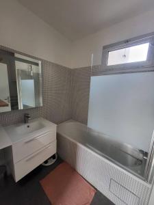 ein Bad mit einem Waschbecken, einer Badewanne und einem Fenster in der Unterkunft T2 charmant rue de Commerce in Paris