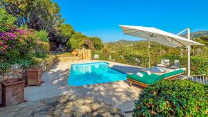 a swimming pool in a yard with an umbrella at VILLA STELLA 6, Emma Villas in Arzachena