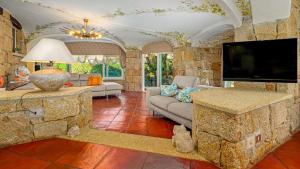 a living room with a tv and a stone wall at VILLA STELLA 6, Emma Villas in Arzachena