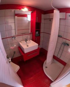La salle de bains rouge et blanche est pourvue d'un lavabo et de toilettes. dans l'établissement Bozikis House! A cosy apartment in the city centre, à Skiathos Chora