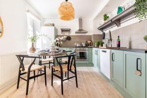 una cocina con armarios verdes, mesa y sillas en Fully Equipped Apartment Close to Malmö & Copenhagen en Vellinge