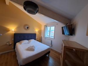 um quarto com uma cama com uma cabeceira azul e uma televisão em Hôtel L'Auberge Canaulaise em Lacanau-Océan