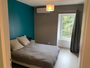 ein Schlafzimmer mit einem Bett mit blauer Wand und einem Fenster in der Unterkunft Le gîte de Moulinas in Giffon
