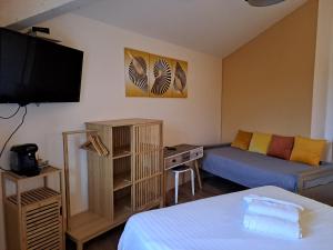 a small living room with a couch and a bed at Hôtel L'Auberge Canaulaise in Lacanau-Océan