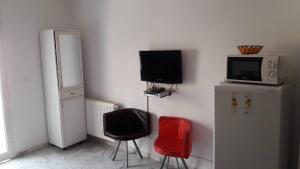 Zimmer mit 2 Stühlen, einem TV und einem Kühlschrank in der Unterkunft NAFISSA RESIDENCE in La Marsa