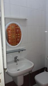 ein weißes Badezimmer mit einem Waschbecken und einem Spiegel in der Unterkunft NAFISSA RESIDENCE in La Marsa