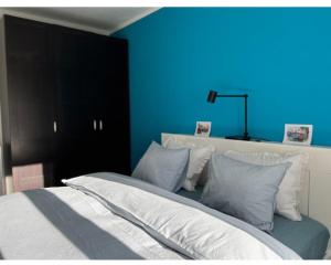 a bedroom with a blue wall and a bed with pillows at Orient pri hokejovom štadióne in Nivy