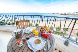 Una mesa con un desayuno en un balcón con la playa. en Family Golf Hotel, en Royan