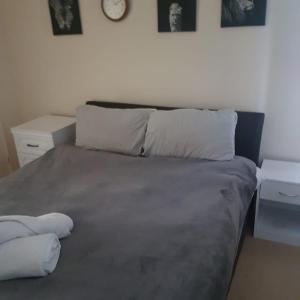 a bed with two pillows and a clock on the wall at Genesis place in Basildon