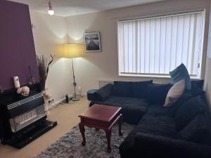 a living room with a blue couch and a table at Genesis place in Basildon