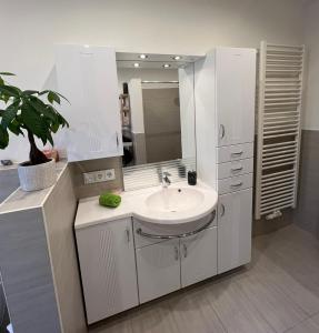 a white bathroom with a sink and a mirror at Ferienwohnung Leopold in Tschernitz