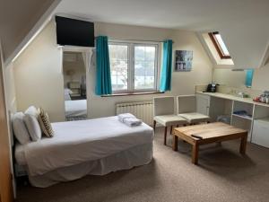 a bedroom with a bed and a table and a desk at The Prince Of Wales Hotel in St Ouen's