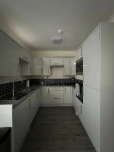 una cocina con armarios blancos y fregadero en 4 Bedroom holiday home, en Woodford