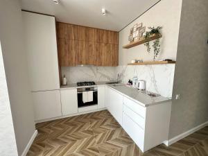 a kitchen with white cabinets and a wooden floor at Apartment 2, Podillya, новобудова in Vinnytsya