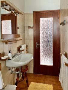 ein Badezimmer mit einem Waschbecken und einer Holztür in der Unterkunft Casa Savina - stupenda vista lago e monti in Plesio