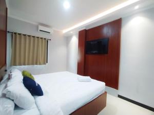 a bedroom with a bed with a tv on the wall at Urbanview Wisma Wirasatya Akpol Semarang by RedDoorz in Candi