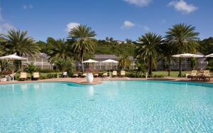 una gran piscina con sillas y sombrillas en The Inn at English Harbour en English Harbour Town