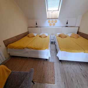 two beds in a room with yellow sheets and a chair at Dolina Miodu - Agro Kaszuby, Sauna, Balia in Borowina