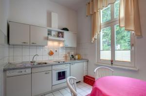 a kitchen with white cabinets and a pink table at Heringsdorf, Villa Lindemann W3 in Heringsdorf