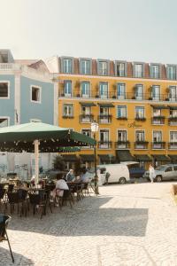 un edificio con mesas y sillas frente a un edificio en Alegria A Lisbon Boutique Hotel, en Lisboa