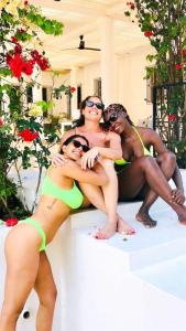 three women in bathing suits sitting on a ledge at Kilimanjaro Twin Rooms Queen Beds in Moshi