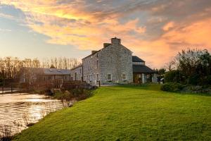 an old stone building on a grassy field next to a river at Lakeland Lodge 9B Arnside , Carnforth ,Lancaster , LA61BH in Carnforth