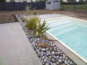 a swimming pool with rocks next to a swimming pool at Maison les coquelicots in Garennes-sur-Eure