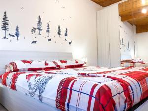 Schlafzimmer mit einem Bett mit einer roten und weißen Decke in der Unterkunft Spazioso Angolo di Paradiso - Residence Erika (TN) in San Valentino