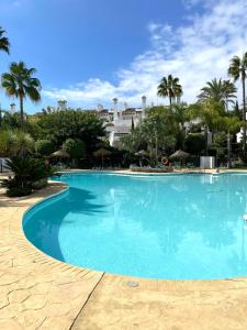 duży basen z palmami i budynek w obiekcie FANTASTIQUE MAISON DE VILLE A COSTALITA w mieście Estepona