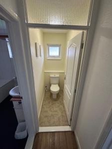 a small bathroom with a toilet and a window at Devon Lodge in Worlingham
