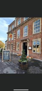 un edificio de ladrillo rojo con un cartel delante en The Red Lion en Lacock