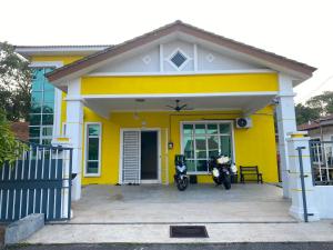 ein gelbes Haus mit einem Motorrad, das davor geparkt ist in der Unterkunft Homestay Sweetcorn in Kampong Alor Gajah