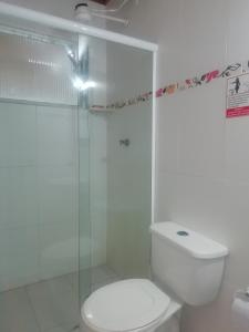 La salle de bains blanche est pourvue de toilettes et d'une douche en verre. dans l'établissement Albergue Rio Vermelho, à Salvador
