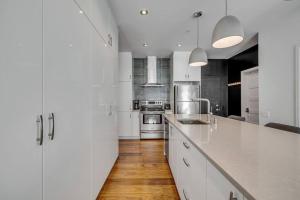 a kitchen with white cabinets and a wooden floor at Initial / Ilot / Downtown Québec in Quebec City