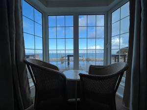 a table and two chairs in front of a large window at The Prince Of Wales Hotel in St Ouen's