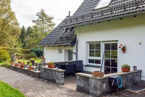 ein weißes Haus mit einer Terrasse mit Pflanzen in der Unterkunft Ferienwohnungen Zum Hasenbahnhof in Kirchhundem