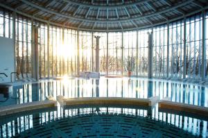 ein großer Pool in einem Gebäude mit einem großen Fenster in der Unterkunft Les Thermes de Spa by La Cour de la Reine Hôtel, Suites & accès gratuit au centre thermal in Spa