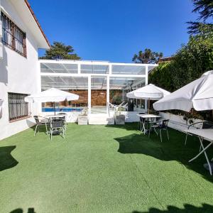 un patio con sombrillas y sillas blancas y una piscina en Posada Mia Nonna en Villa General Belgrano