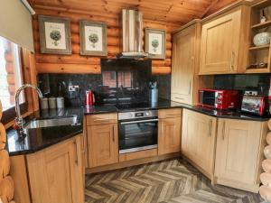 a kitchen with wooden cabinets and a stove top oven at 10 Water's Edge in Morpeth