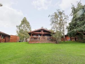 a log cabin with a green lawn in front of it at 10 Water's Edge in Morpeth