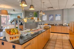 a large kitchen with fruits and vegetables on a counter at ibis Hotel Frankfurt Messe West in Frankfurt/Main