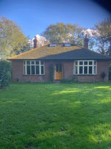 a brick house with a yellow door in a yard at Woodland Retreat, Market Lane, Blundeston, Lowestoft in Blundeston