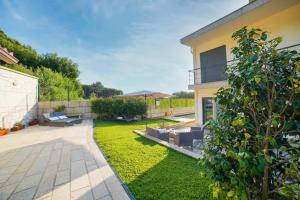 une cour avec une terrasse et de la pelouse dans l'établissement Magníficos Dias Atlânticos, à Moledo