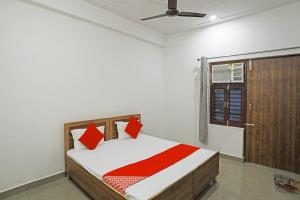 a bedroom with a bed with red pillows and a window at OYO Flagship Hotel Yuvraj Plaza in Garhi Harsāru