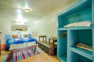 1 dormitorio con litera azul y mesa en Kasbah Tizzarouine en Boumalne