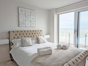 a bedroom with a large bed with a view of the ocean at West Lodge, Bognor Regis in Bognor Regis