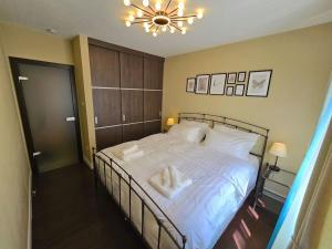 Un dormitorio con una cama con sábanas blancas y una lámpara de araña. en Berzenczey apartment, en Budapest