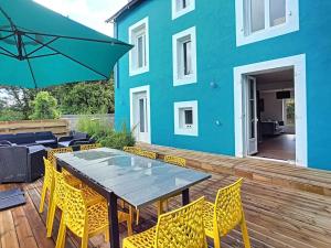 una terraza de madera con mesa y sillas y un edificio azul en Ti-hañv - la maison d'été, en Crozon