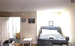 um quarto com uma cama e um relógio na parede em Lt Properties studio apartment Ground floor 1 em Luton