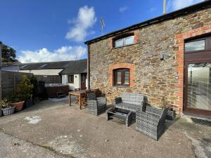 uma casa de tijolos com cadeiras e uma mesa em frente em The Granary Stunning Barn Conversion em Broadwoodkelly